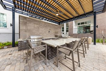 a patio with a long table with chairs and a grill at The Monroe Apartments, Austin, 78741
